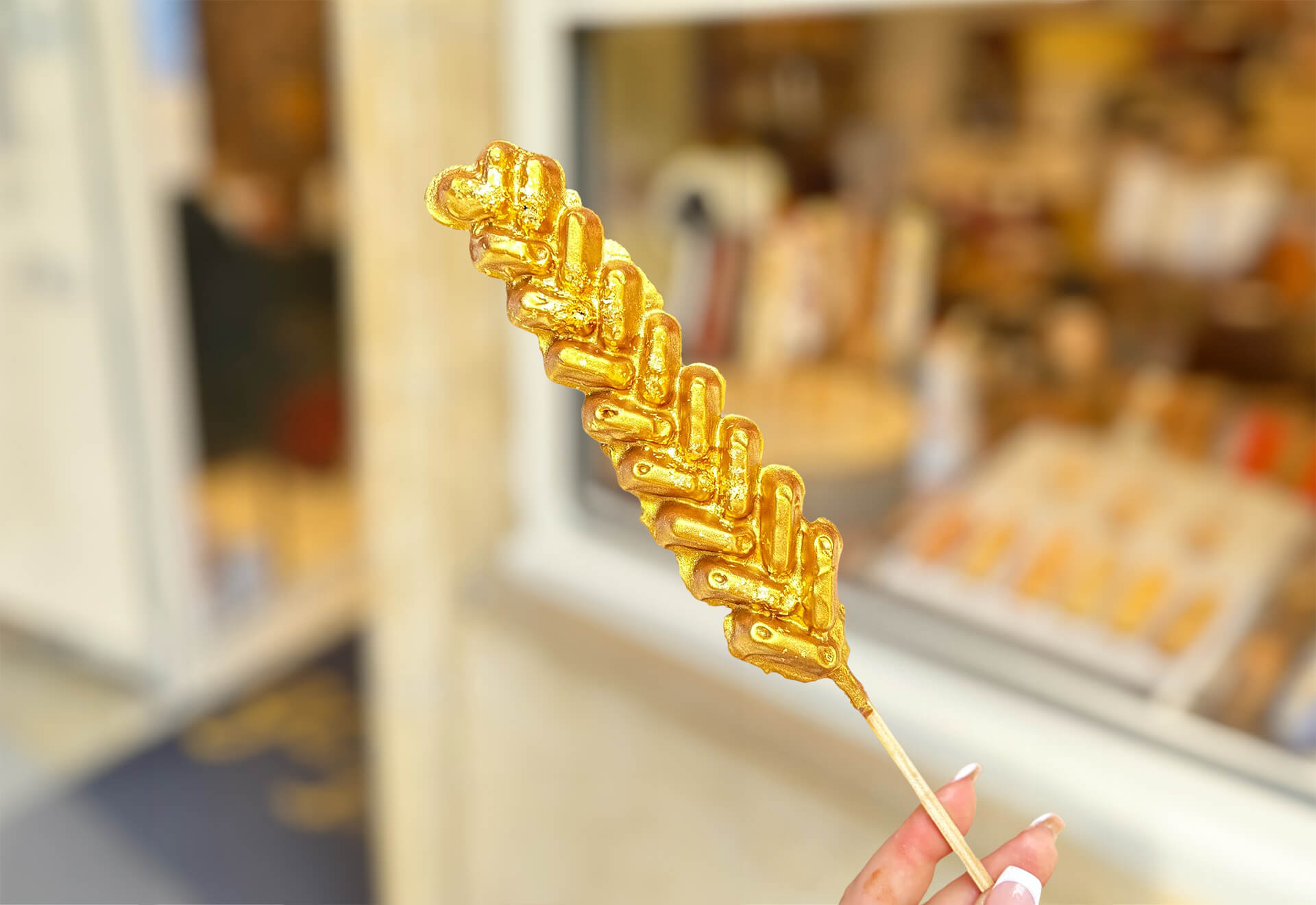 Person holding a waffle covered in edible gold leaf in the streets of Bruges.